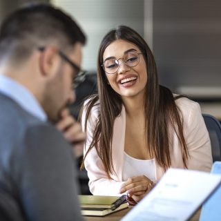 Young attractive woman during job interview Portrait of young female client or candidate sitting at table, talking to male manager and smiling in office. Job interview or consultancy concept. Young attractive woman during job interview
