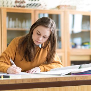Young female college student in chemistry class, writing notes. Focused student in classroom. Authentic Education concept. Young female college student in chemistry class, writing notes. Focused student in classroom. Authentic Education concept.